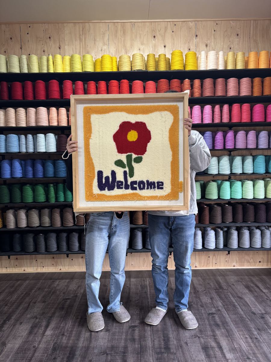 ふたりで仕上げたWelcomeラグを持つ参加者